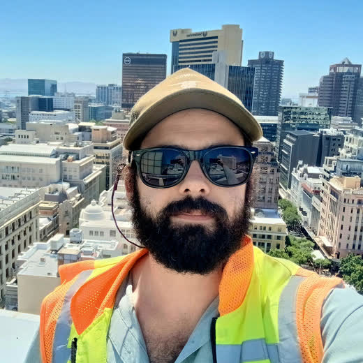 Nicholas Petersen on a rooftop in a hi-vis vest, Cape Town skyline behind